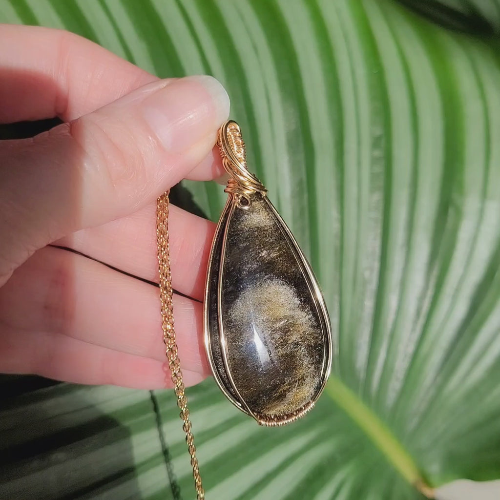 Vidéo pendentif obsidienne dorée wire wrapping montrant reflets changeants et profonds