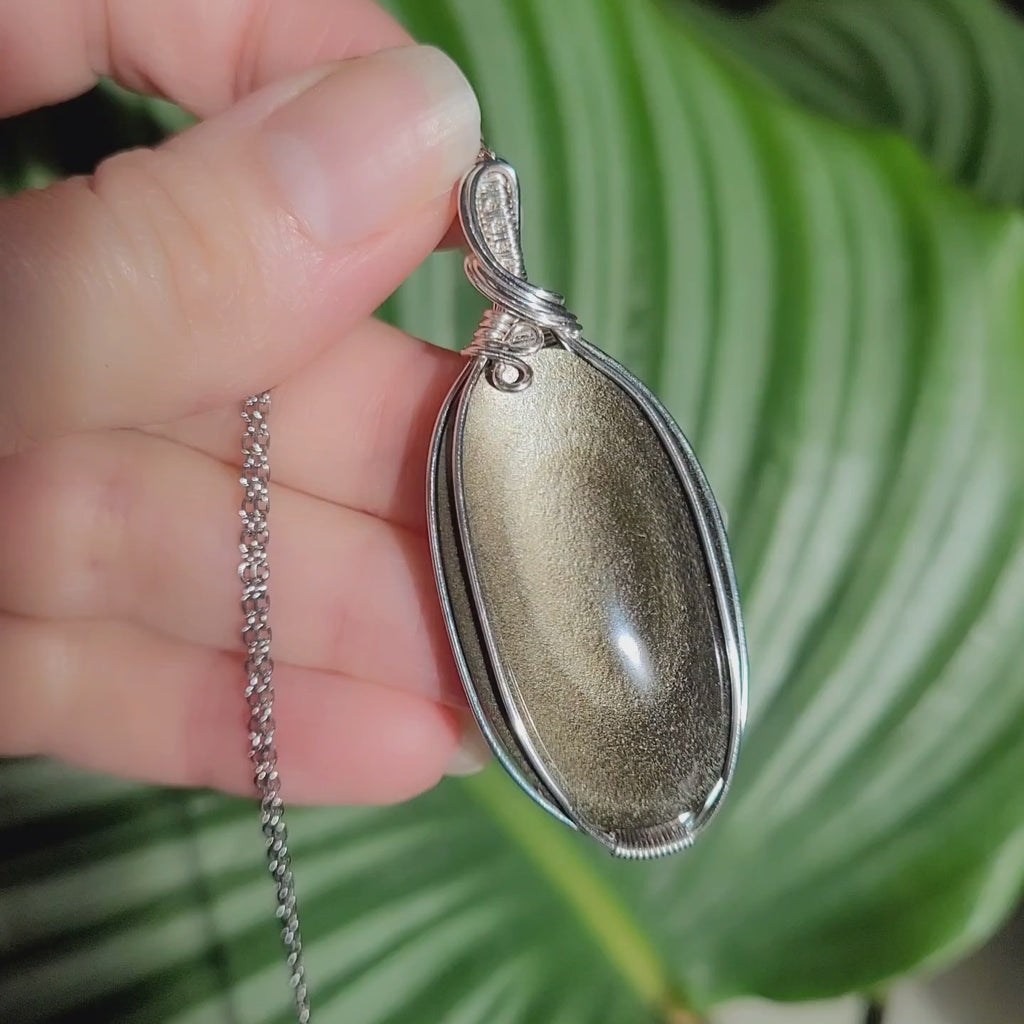 Vidéo pendentif obsidienne dorée wire wrapping montrant reflets changeants 