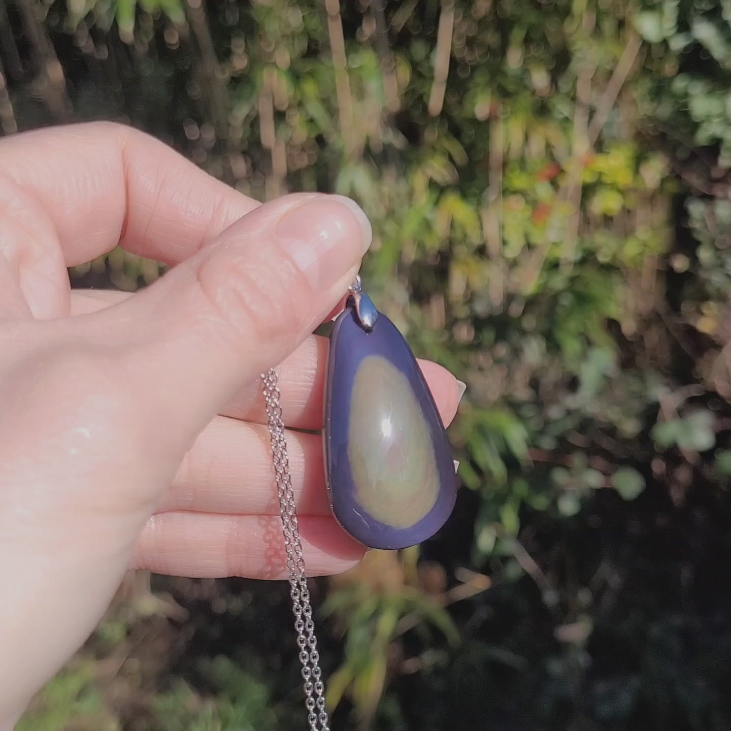 Vidéo rotation du bijou pendentif en obsidienne manta huichol montrant des reflets violet et jaune changeants 
