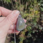 Vidéo rotation du bijou pendentif en obsidienne manta huichol montrant des reflets changeants verts avec pointes de bleu et jaune